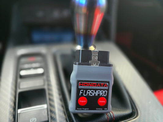 A Hondata Flashpro Mini ECU tuning device for 2017+ Honda Civic Type R FK8 FL5 resting on shifter showing front view of FlashPro device fp-ctr-us